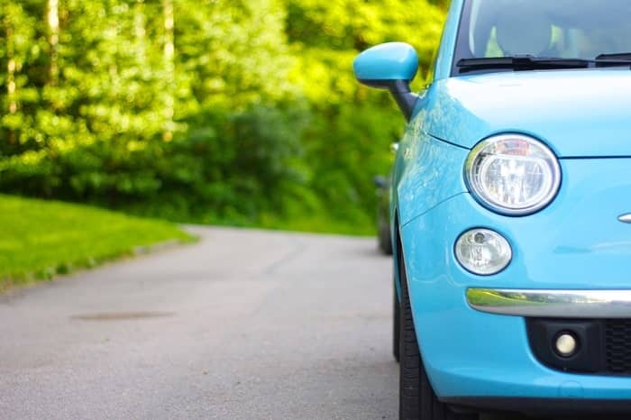 Une Fiat 500 bleue garée avec une pression de pneus appropriée est située sur le bord d'une route.