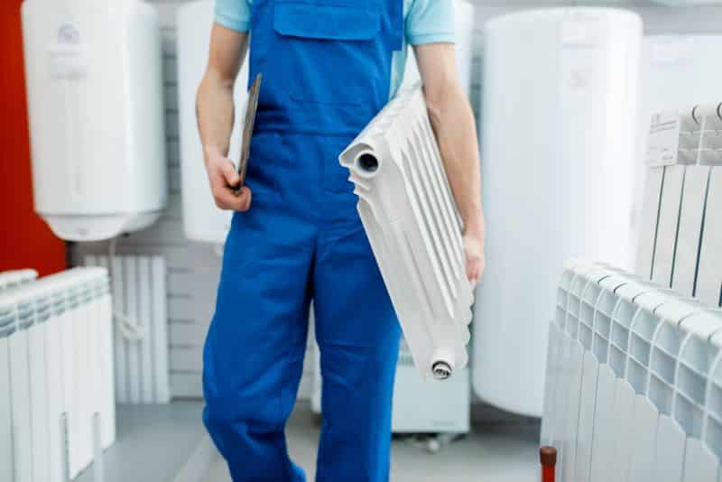 Plumber holds heating radiator, plumbering store