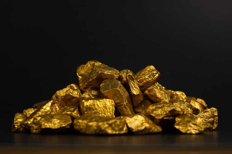 A pile of gold nuggets or gold ore on black background