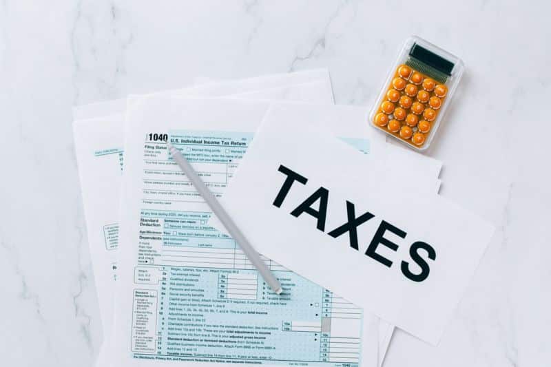 Une pile de formulaires fiscaux et un stylo sur une table en marbre.