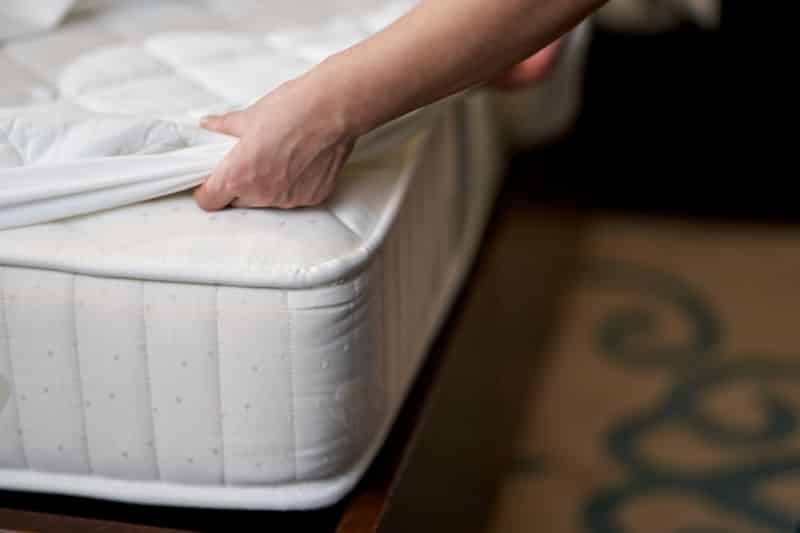 Housemaid is changing bedding in hotel room