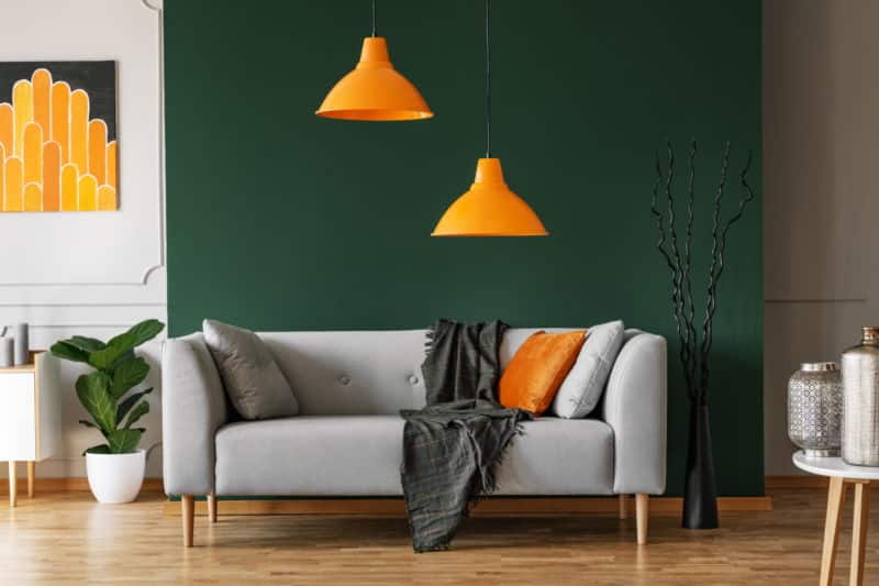 Un salon avec un canapé gris et des lampes orange.