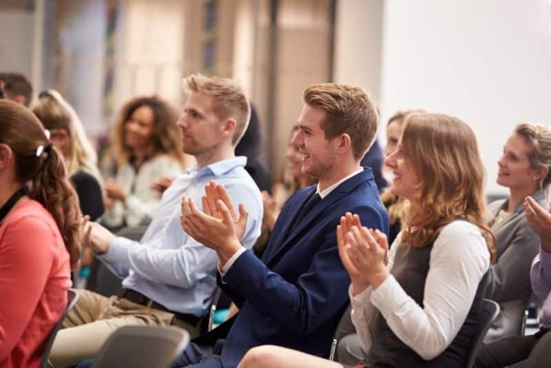 Un groupe de personnes applaudissant lors d'une conférence.