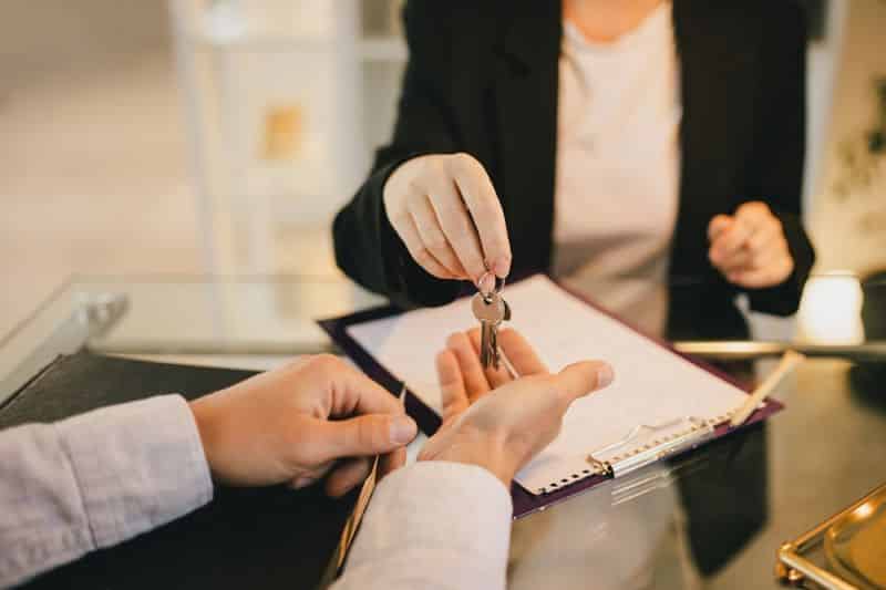 Une femme remettant une clé à un homme en costume d'affaires.