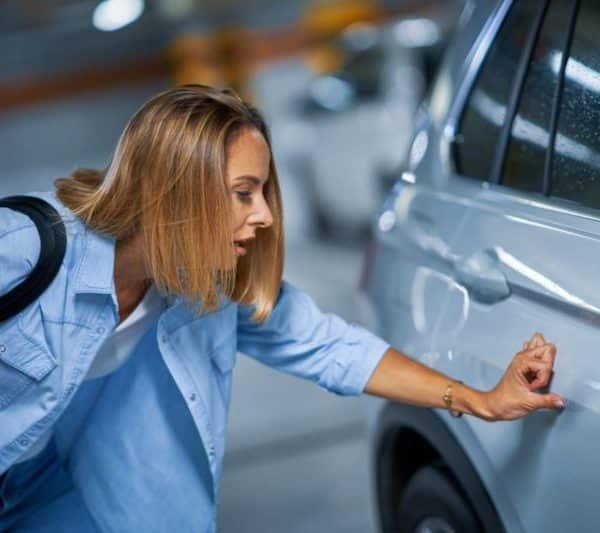 Une femme regarde une voiture dans un parking.