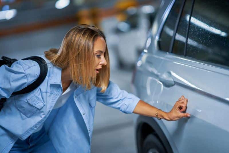 Une femme regarde une voiture dans un parking.