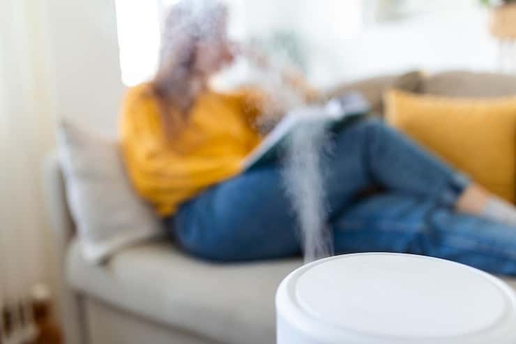 Une femme assise sur un canapé avec un humidificateur.