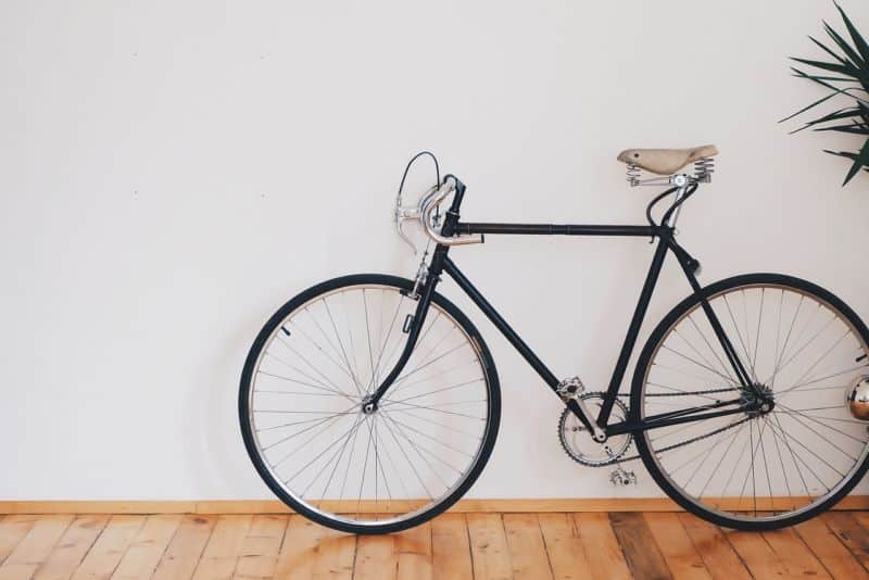 Un vélo appuyé contre un mur avec une plante en pot.