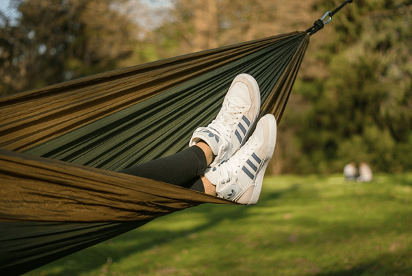 Les pieds d'une personne dans un hamac avec des baskets.