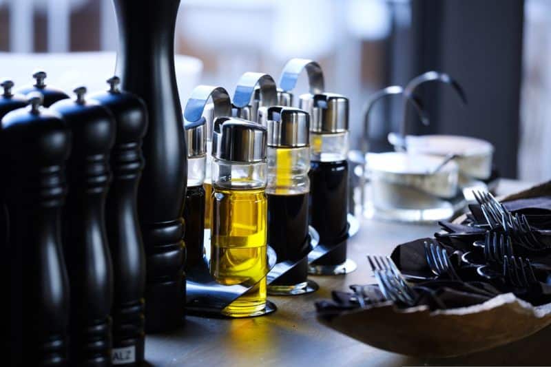 Une table avec une bouteille d'huile d'olive, des fourchettes et des cuillères.