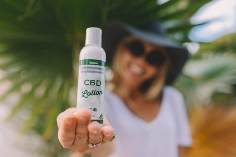 Une femme tenant une bouteille de lotion cbd.