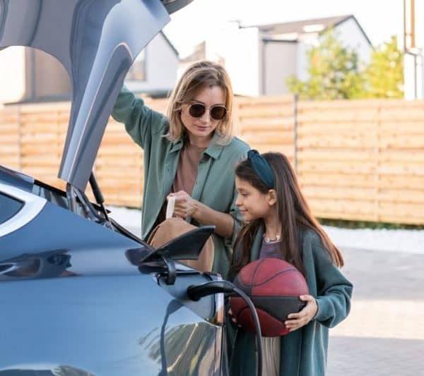 Une mère et sa fille ouvrent le coffre d'une voiture.