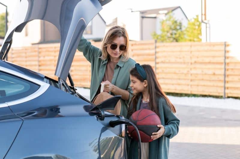 Une mère et sa fille ouvrent le coffre d'une voiture.