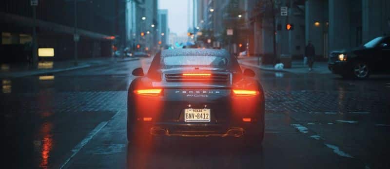 Une Porsche 911 roulant dans une rue de la ville la nuit.