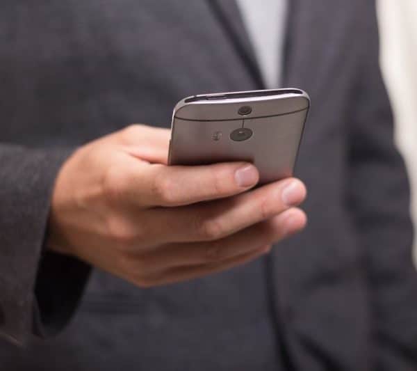 Un homme en costume tient un téléphone portable.