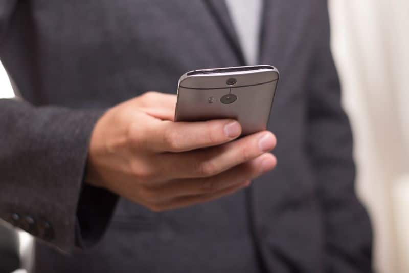 Un homme en costume tient un téléphone portable.