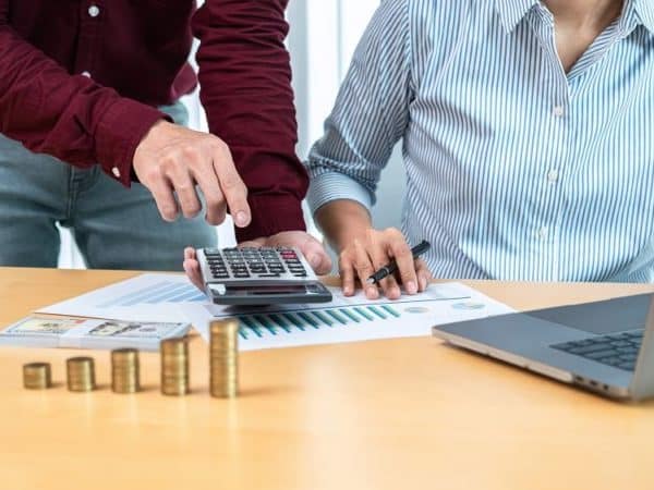Un homme et une femme regardant une calculatrice et des pièces de monnaie.