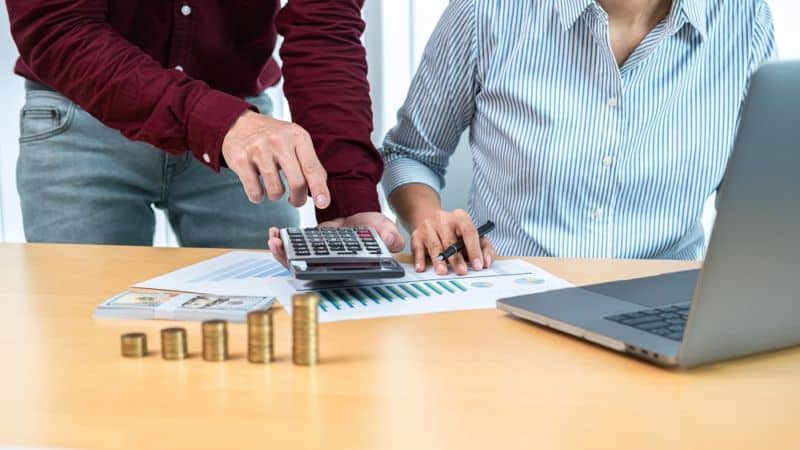 Un homme et une femme regardant une calculatrice et des pièces de monnaie.