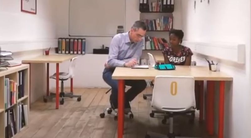 Un homme et une femme assis à un bureau dans une pièce.