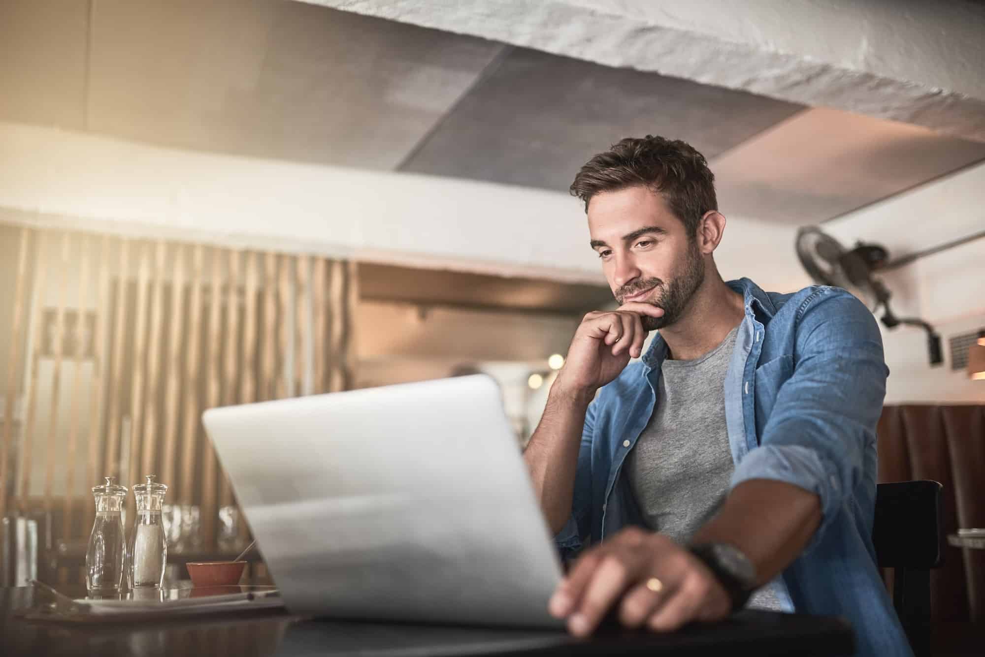 Connected to a day of productivity. Shot of a handsome young man using a laptop in a coffee shop.