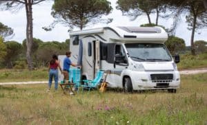 Deux Personnes Debout à Côté D'un Camping Car Dans Un Champ.