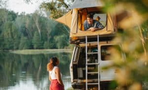 Un Homme Et Une Femme Debout à Côté D'un Camping Car Sur Un Lac.