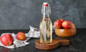 Une Bouteille De Vinaigre De Cidre De Pomme Sur Une Planche à Découper En Bois.