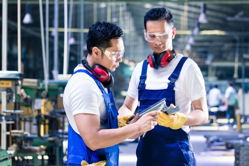 Deux Ouvriers Dans Une Usine Regardent Une Tablette.