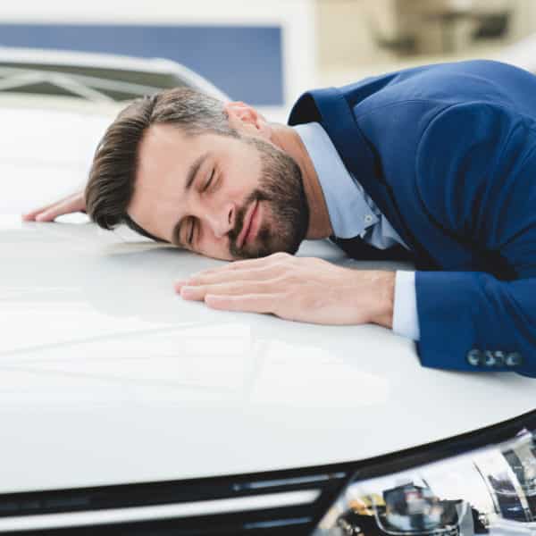 Un Homme En Costume Dort Sur Le Capot D’une Voiture.
