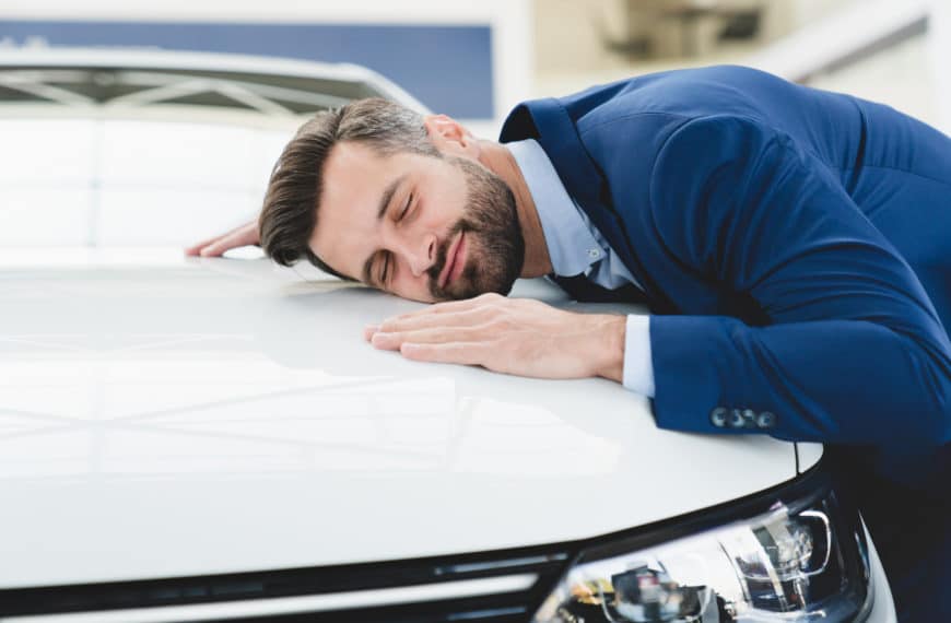 Un Homme En Costume Dort Sur Le Capot D’une Voiture.