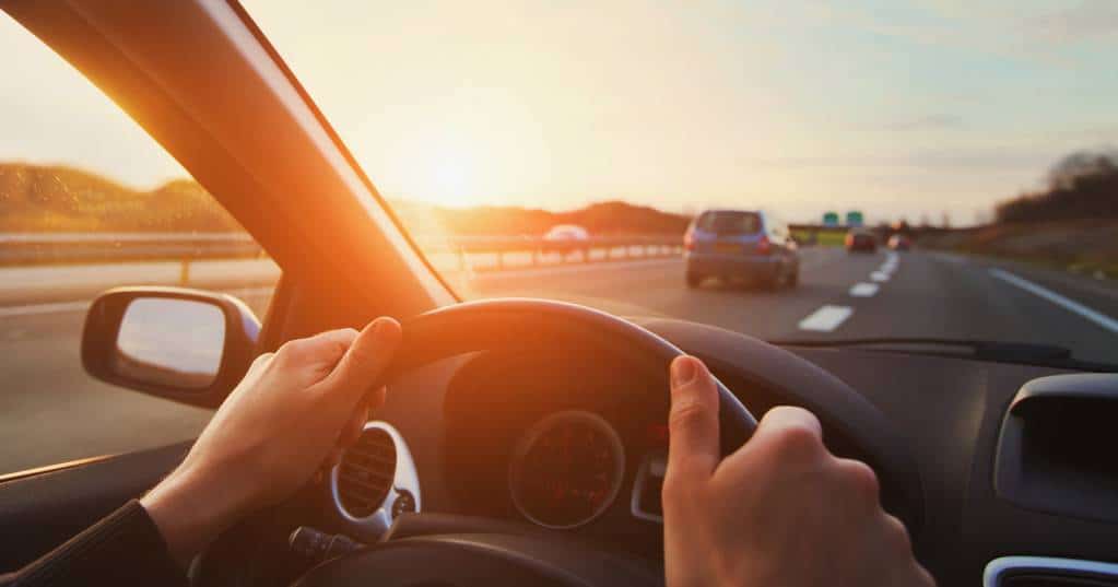 Une Femme Conduisant Une Voiture Sur Une Autoroute Au Coucher Du Soleil.