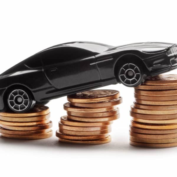 Une petite voiture noire se trouve au sommet de piles de pièces de monnaie.