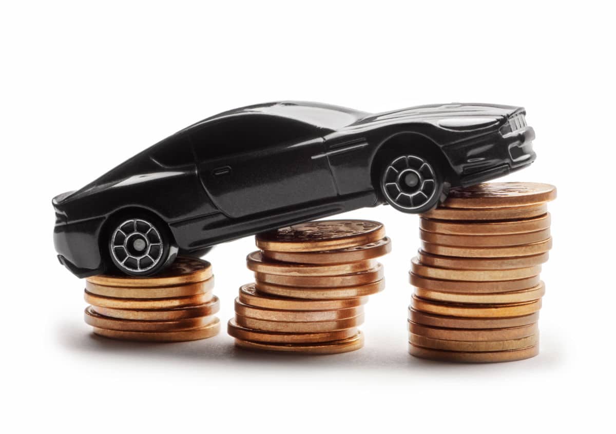 Une petite voiture noire se trouve au sommet de piles de pièces de monnaie.
