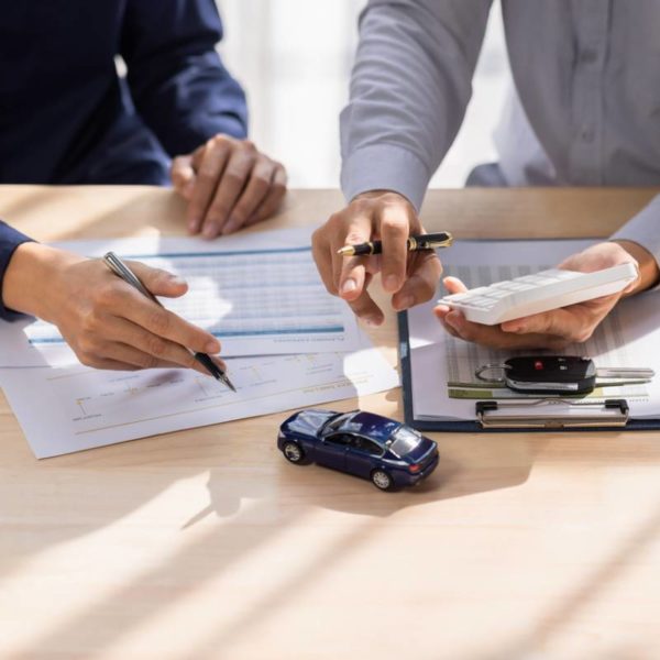 Un Homme Et Une Femme Sont Assis à Une Table Avec Des Papiers Et Une Petite Voiture.