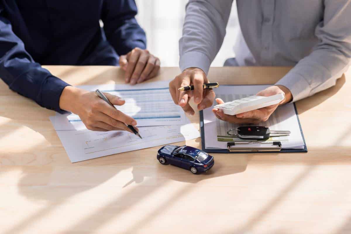 Un Homme Et Une Femme Sont Assis à Une Table Avec Des Papiers Et Une Petite Voiture.