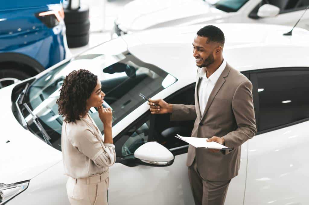 Un Homme Et Une Femme Discutant De L’achat D’une Nouvelle Voiture Chez Un Concessionnaire.