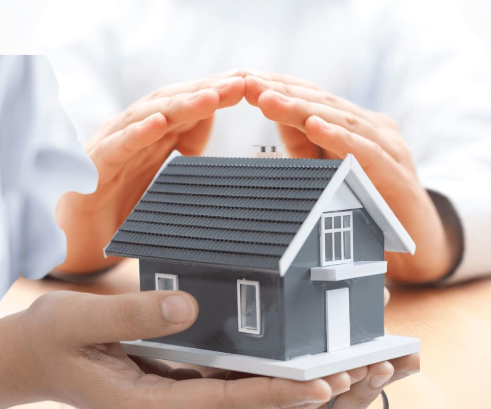 Deux mains tenant une maquette, représentant une maison protégée par une assurance d'habitation.