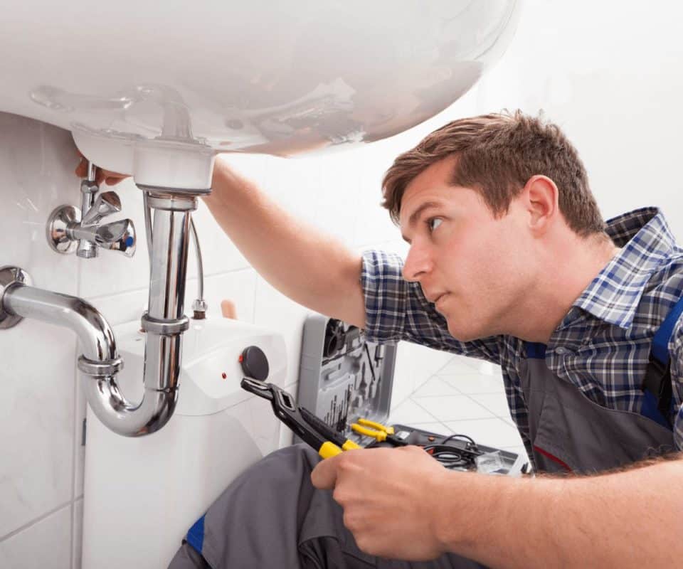 Un Plombier répare un lavabo dans le cadre de l'entretien d'une maison.