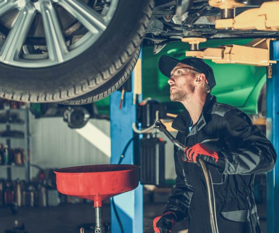 Un Mécanicien professionnel effectue l'entretien automobile d'une voiture dans un garage.