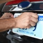 Un Homme Met Une Plaque D'immatriculation Sur Une Voiture.