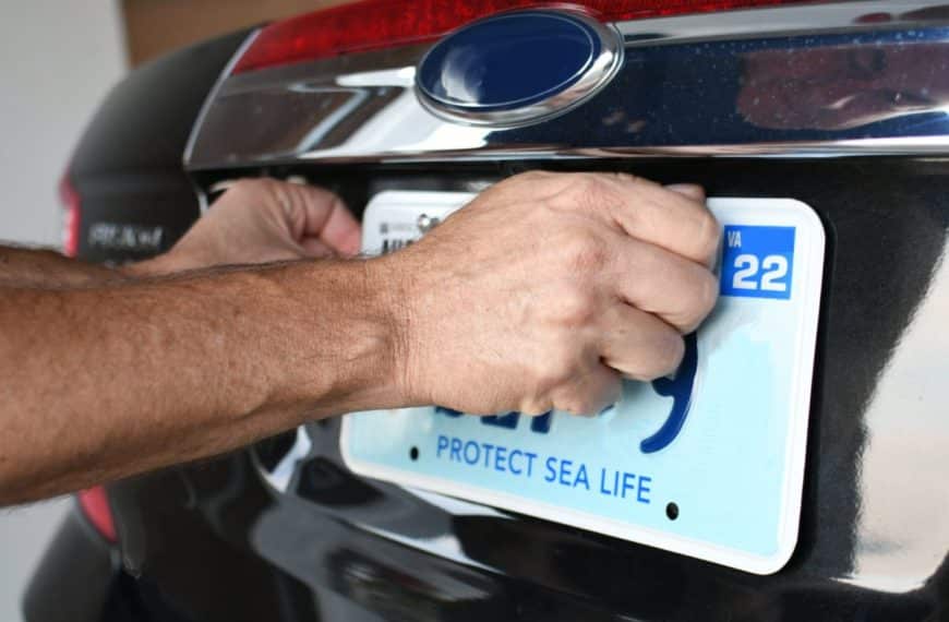 Un Homme Met Une Plaque D'immatriculation Sur Une Voiture.