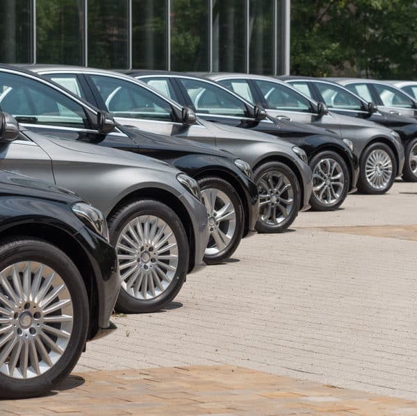 Une Rangée De Voitures Mercedes Benz Garées Devant Un Bâtiment.