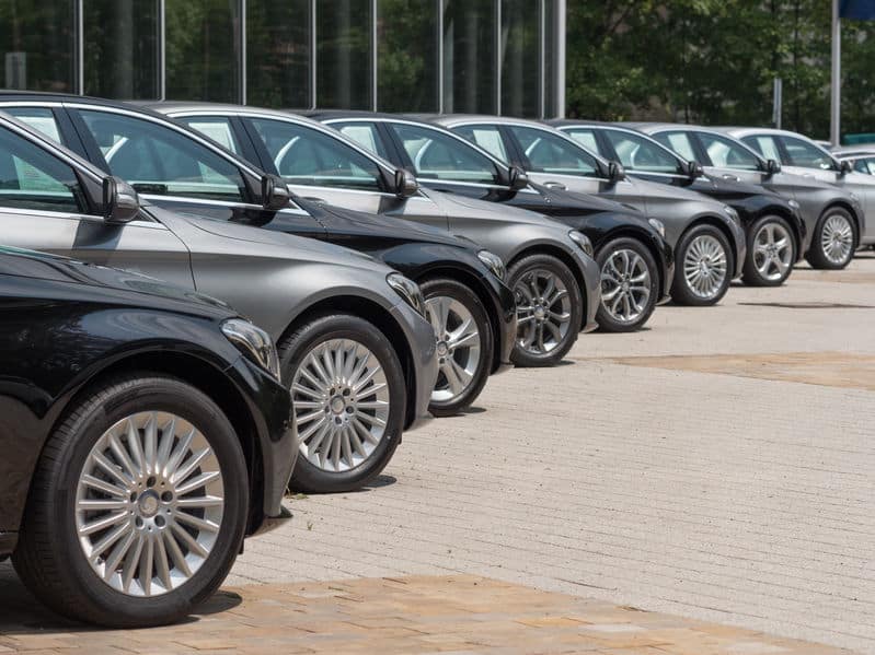 Une Rangée De Voitures Mercedes Benz Garées Devant Un Bâtiment.