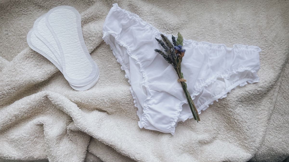 Une Paire De Culottes Blanches Et Une Fleur De Lavande Sur Une Couverture Blanche.