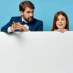 Un Homme Et Une Femme Tiennent Un Tableau Vierge Sur Un Fond Bleu.