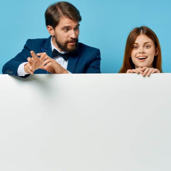 Un Homme Et Une Femme Tiennent Un Tableau Vierge Sur Un Fond Bleu.