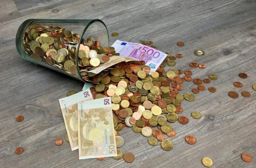 Un Bocal En Verre Rempli De Pièces Sur Un Plancher En Bois.