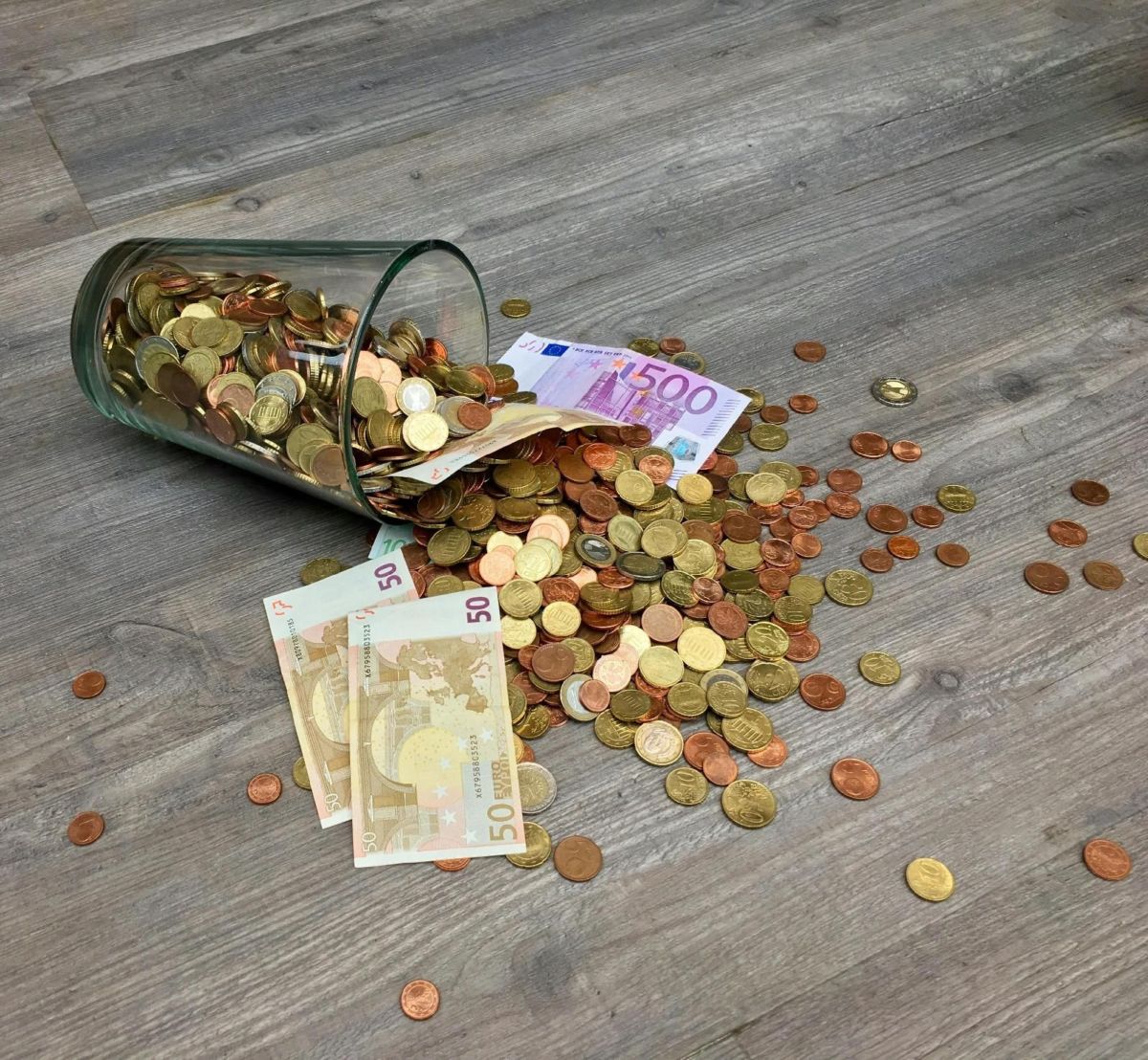 Un Bocal En Verre Rempli De Pièces Sur Un Plancher En Bois.