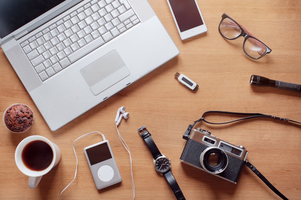 Un Ordinateur Portable, Un Téléphone, Un Appareil Photo Et D'autres Objets Sur Une Table En Bois.