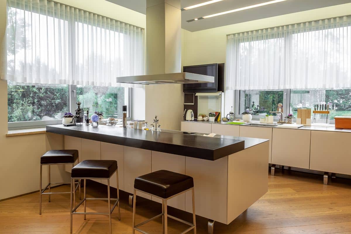 Une cuisine fonctionnelle moderne avec des tabourets et une fenêtre.